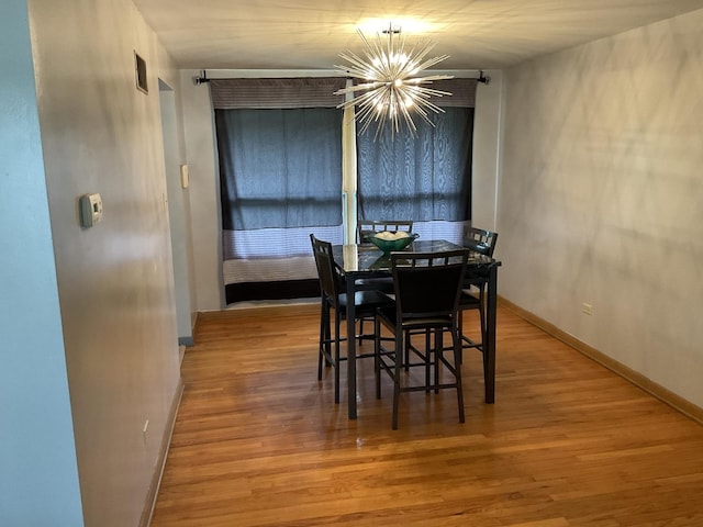 dining space featuring wood-type flooring and a chandelier