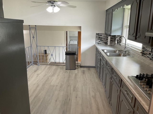 kitchen featuring tasteful backsplash, stainless steel gas stovetop, sink, ceiling fan, and light hardwood / wood-style floors