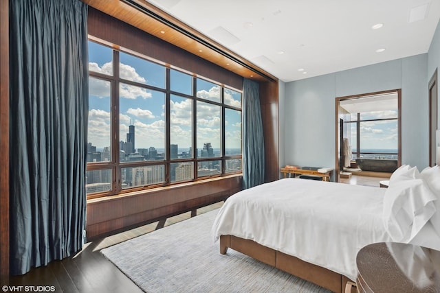 bedroom featuring recessed lighting, a city view, and wood finished floors