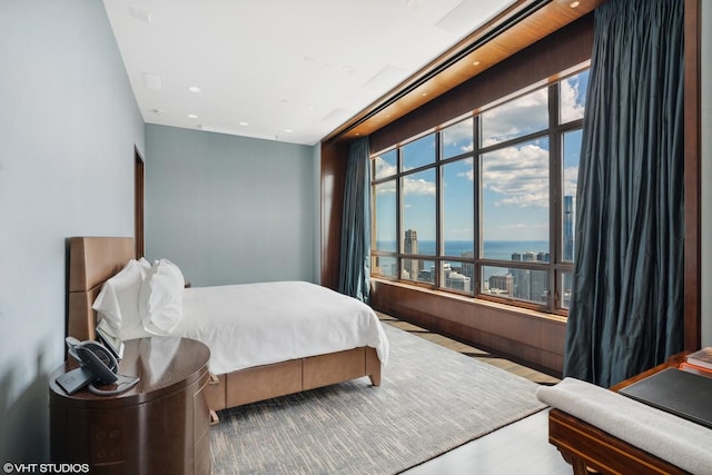 bedroom featuring recessed lighting, multiple windows, a water view, and wood finished floors