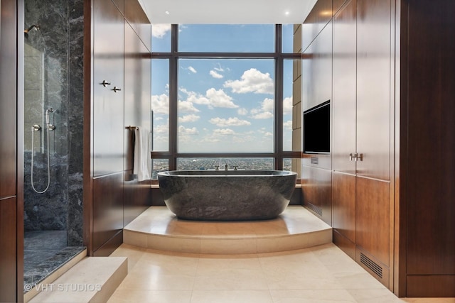 full bath featuring a wealth of natural light, tiled shower, and a freestanding bath