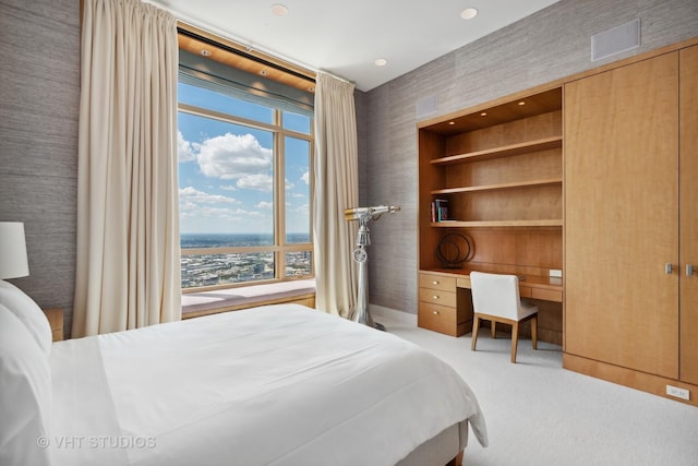 bedroom with visible vents, carpet flooring, and built in desk