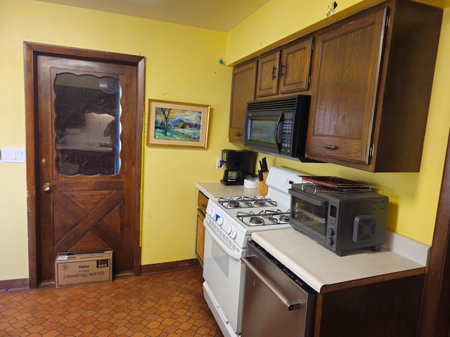 kitchen featuring dark tile patterned floors, white gas range oven, and dishwasher