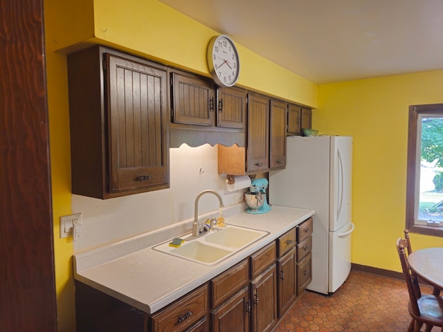 kitchen with sink, tile patterned flooring, white refrigerator, and dark brown cabinets