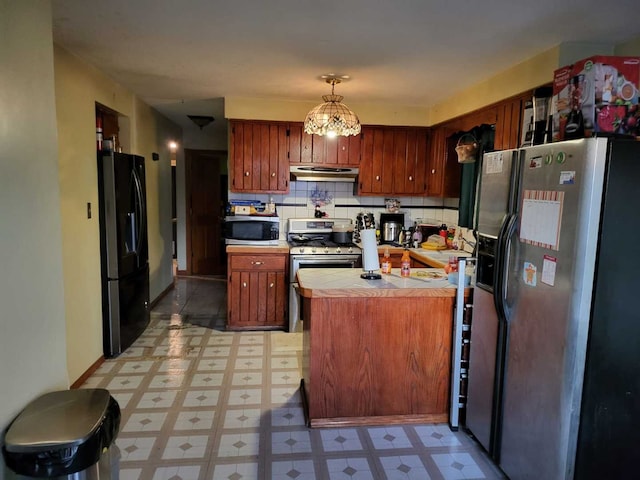 kitchen with decorative light fixtures, tasteful backsplash, tile countertops, and appliances with stainless steel finishes