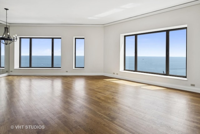 unfurnished room featuring a water view, dark hardwood / wood-style flooring, an inviting chandelier, and a wealth of natural light