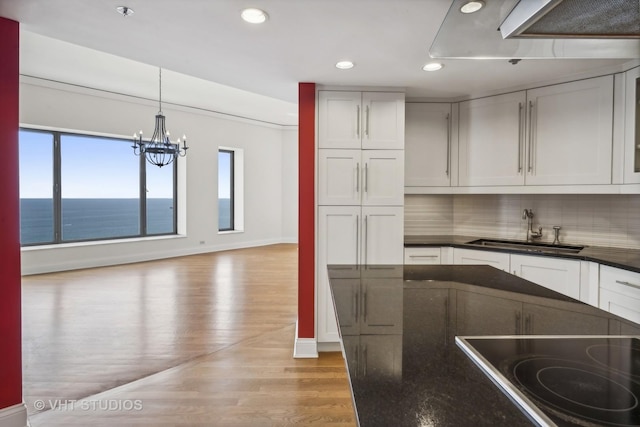 kitchen with a water view, sink, pendant lighting, and white cabinets