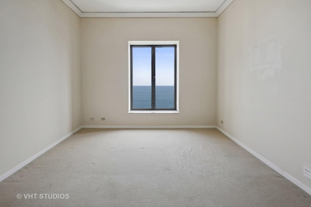 empty room featuring crown molding, a water view, and light colored carpet