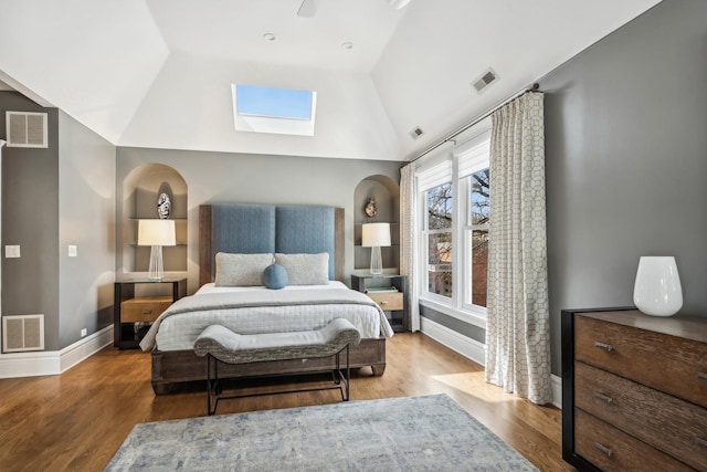 bedroom featuring vaulted ceiling with skylight, visible vents, and wood finished floors