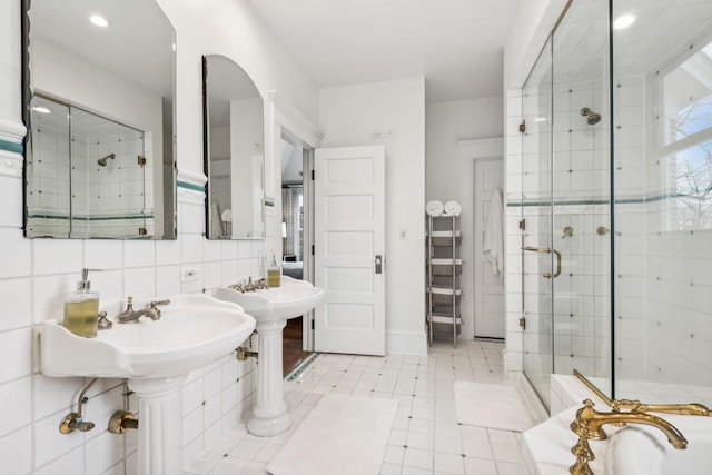 bathroom with an enclosed shower, tile walls, dual sinks, tile patterned flooring, and backsplash