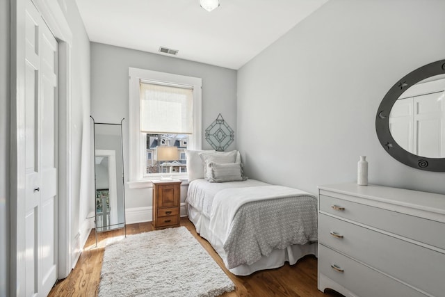 bedroom featuring wood finished floors, visible vents, and baseboards