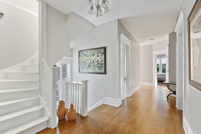 interior space with baseboards, a chandelier, wood finished floors, and an upstairs landing