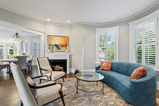 living room featuring hardwood / wood-style flooring, crown molding, a chandelier, and a brick fireplace