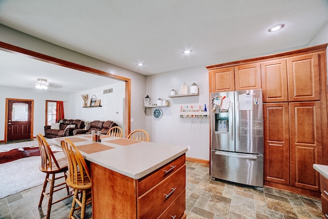 kitchen with a kitchen bar, a kitchen island, light tile patterned floors, and stainless steel fridge with ice dispenser