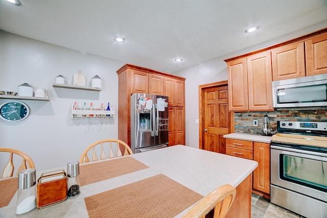 kitchen featuring appliances with stainless steel finishes, light tile patterned floors, and backsplash