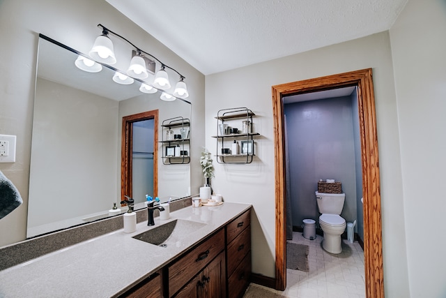 bathroom with tile patterned flooring, toilet, vanity, and a textured ceiling