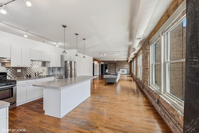 kitchen featuring stainless steel appliances, backsplash, white cabinets, and decorative light fixtures