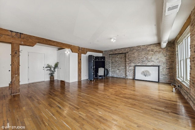 unfurnished living room with brick wall and hardwood / wood-style floors