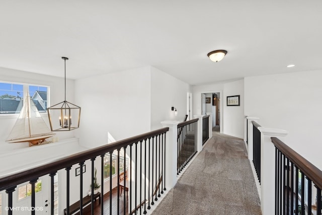 hallway with carpet and a notable chandelier