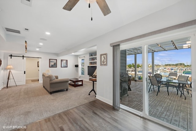 living room featuring hardwood / wood-style flooring, a barn door, and ceiling fan