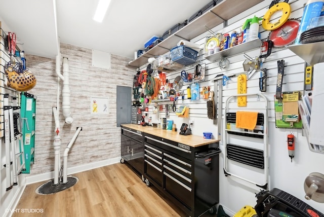 interior space with electric panel, wood walls, light hardwood / wood-style floors, and a workshop area