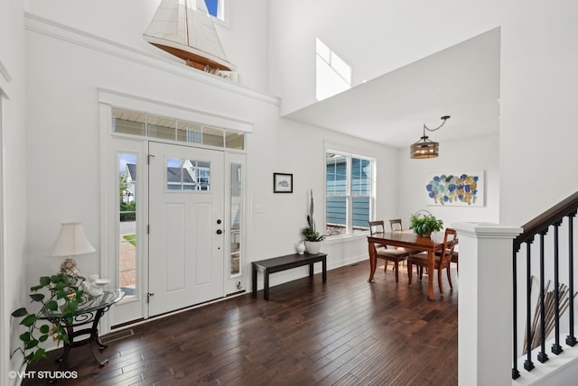 entryway with a towering ceiling and dark wood-type flooring