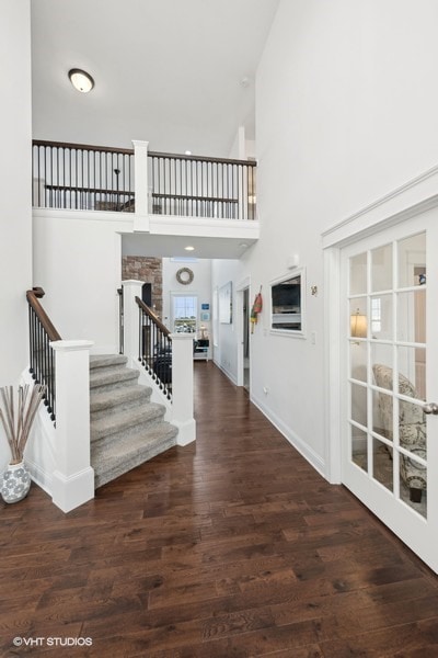 entryway featuring dark hardwood / wood-style flooring, a towering ceiling, and french doors