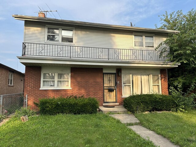 view of front of property featuring a balcony and a front yard