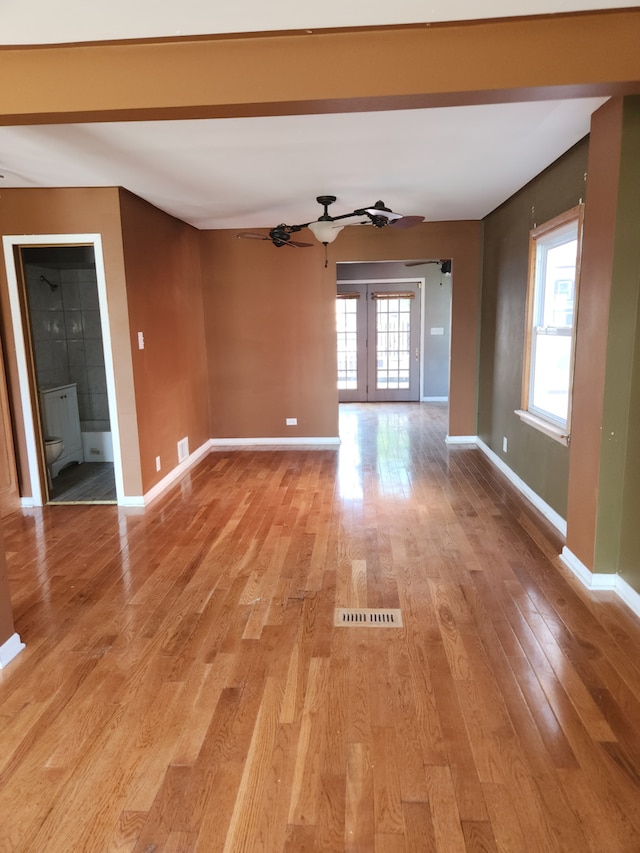 empty room featuring ceiling fan, light wood-type flooring, and french doors