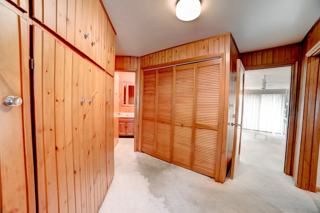 corridor featuring wood walls and light colored carpet