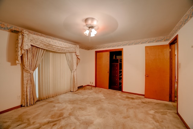 unfurnished bedroom featuring light colored carpet, a closet, ceiling fan, and a walk in closet