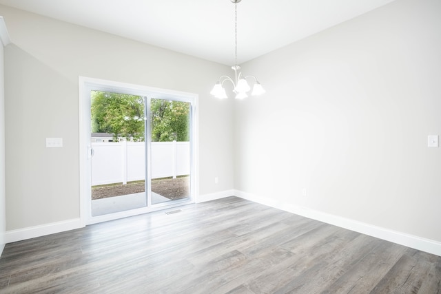 spare room with wood-type flooring and a notable chandelier