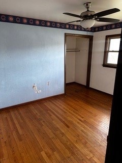 unfurnished bedroom featuring ceiling fan, hardwood / wood-style floors, and a closet