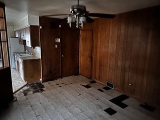 unfurnished room featuring wooden walls and ceiling fan