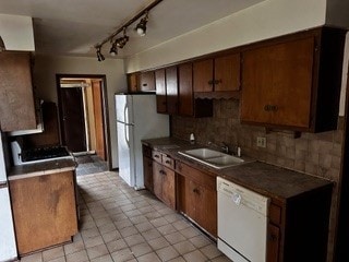 kitchen with decorative backsplash, light tile patterned floors, white appliances, and sink