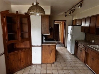 kitchen with white fridge, rail lighting, range, and light tile patterned floors