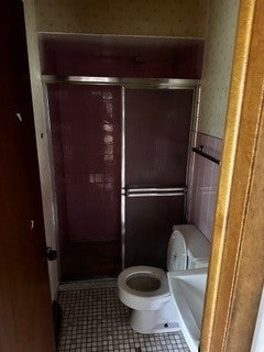 bathroom with a shower with shower door, tile patterned floors, and toilet