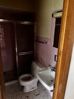 bathroom featuring a shower with door, toilet, tile patterned floors, and sink