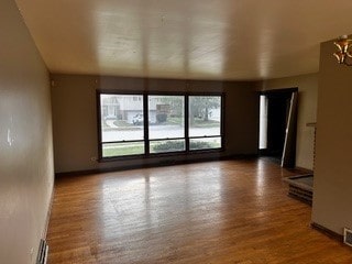 spare room with a notable chandelier and hardwood / wood-style floors