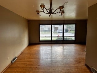 spare room featuring hardwood / wood-style floors, a chandelier, and a healthy amount of sunlight