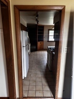 kitchen with black electric range, white refrigerator, and light tile patterned floors