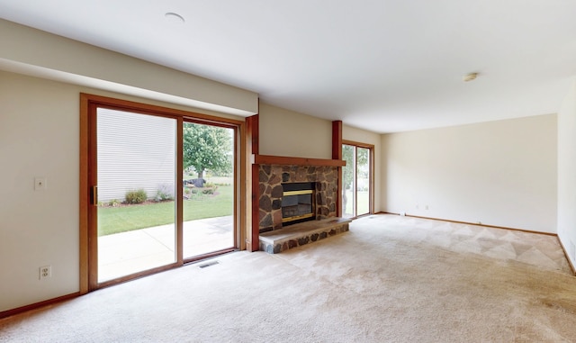 unfurnished living room featuring a stone fireplace and light carpet