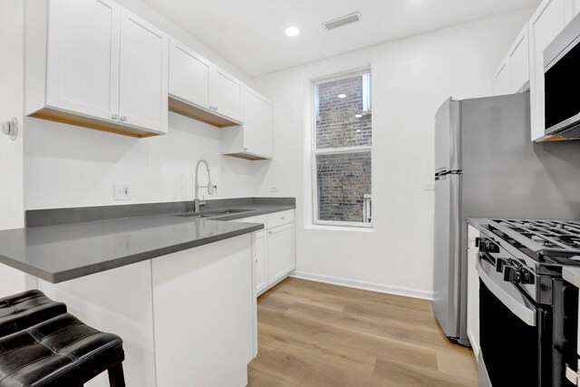 kitchen featuring white cabinets, sink, light wood-type flooring, kitchen peninsula, and stainless steel appliances