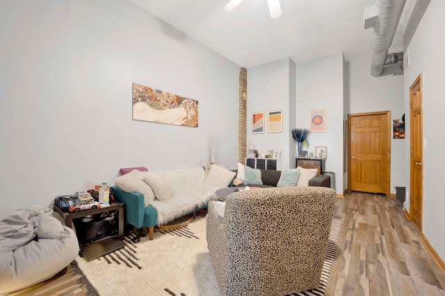 living room featuring a high ceiling, light wood-type flooring, and ceiling fan