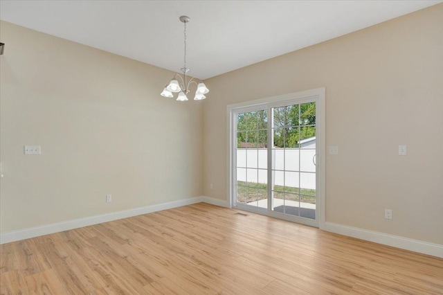 704 Justice St, Tuscola, IL 61953 - spare room featuring light wood-type flooring, a chandelier, and baseboards