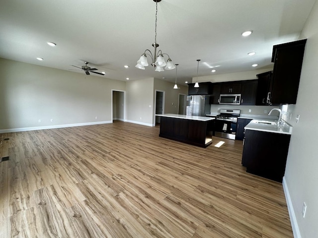 kitchen with a kitchen island, a sink, stainless steel appliances, light countertops, and open floor plan