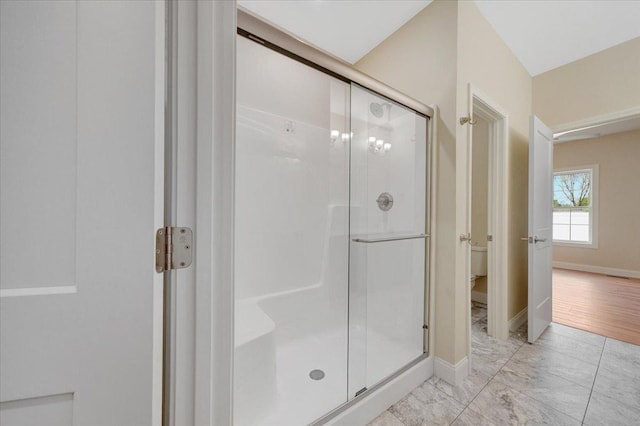 704 Justice St, Tuscola, IL 61953 - full bathroom featuring a stall shower, baseboards, marble look tile flooring, and toilet