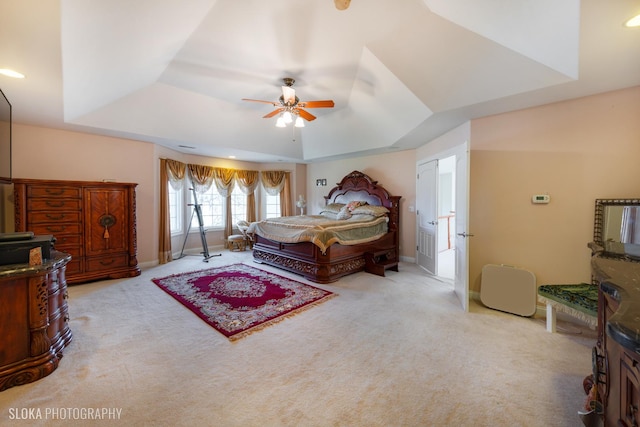 carpeted bedroom featuring ceiling fan and a raised ceiling