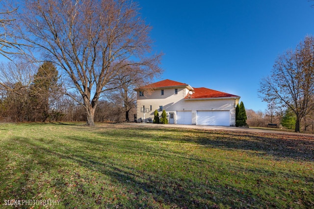 view of side of property featuring a garage and a lawn