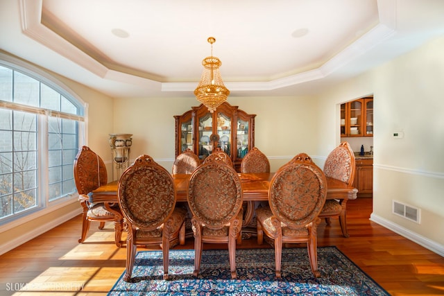 dining room featuring a wealth of natural light, light wood-type flooring, and a tray ceiling